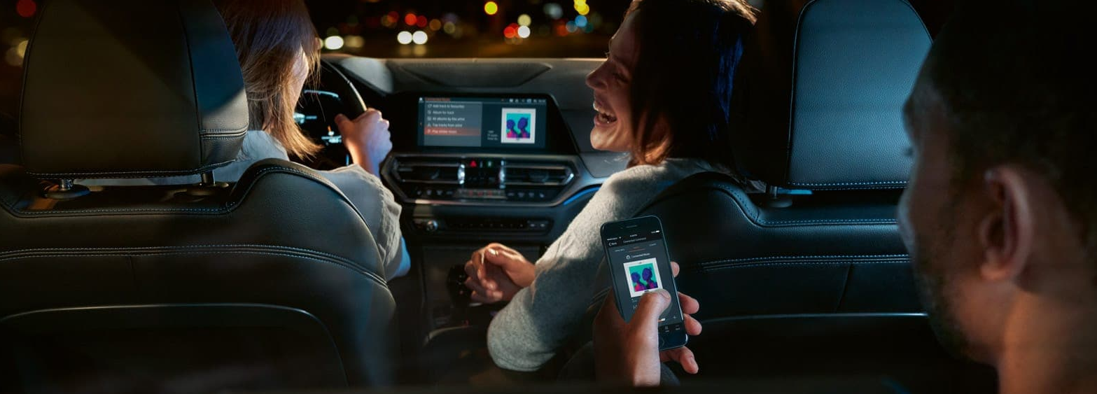 people sitting in a BMW 3 series car enjoying music through the infotainment