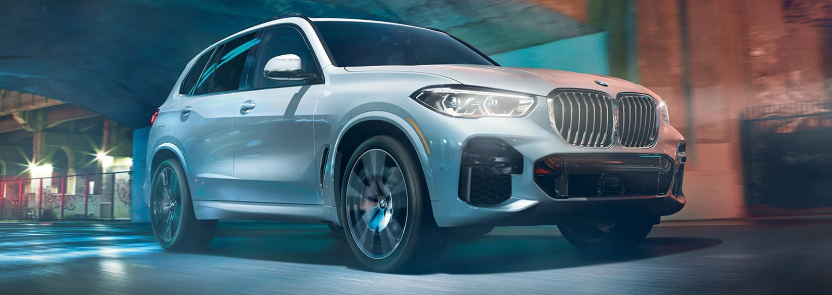 BMW X5 with white paint drive on a street entering a tunnel